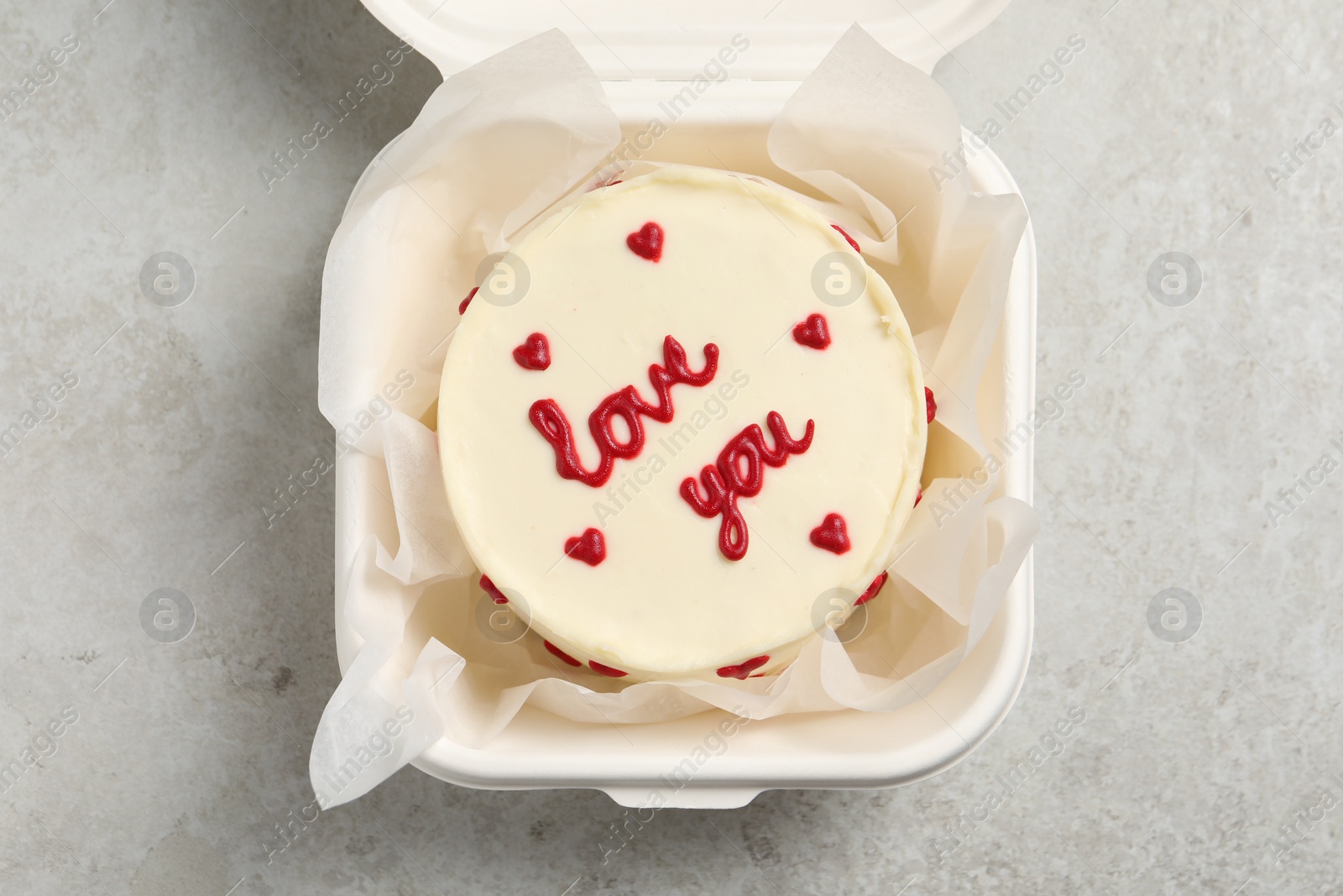 Photo of Bento cake with Love You text in takeaway box on light grey table, top view. St. Valentine's day surprise