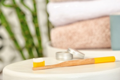 Bamboo toothbrush with paste on table against blurred background