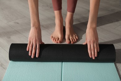 Woman rolling yoga mat on floor, closeup