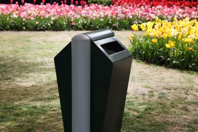 Photo of Trash bin near flowers in park on spring day