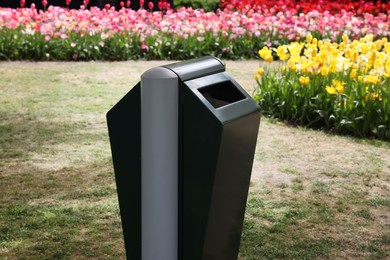 Trash bin near flowers in park on spring day