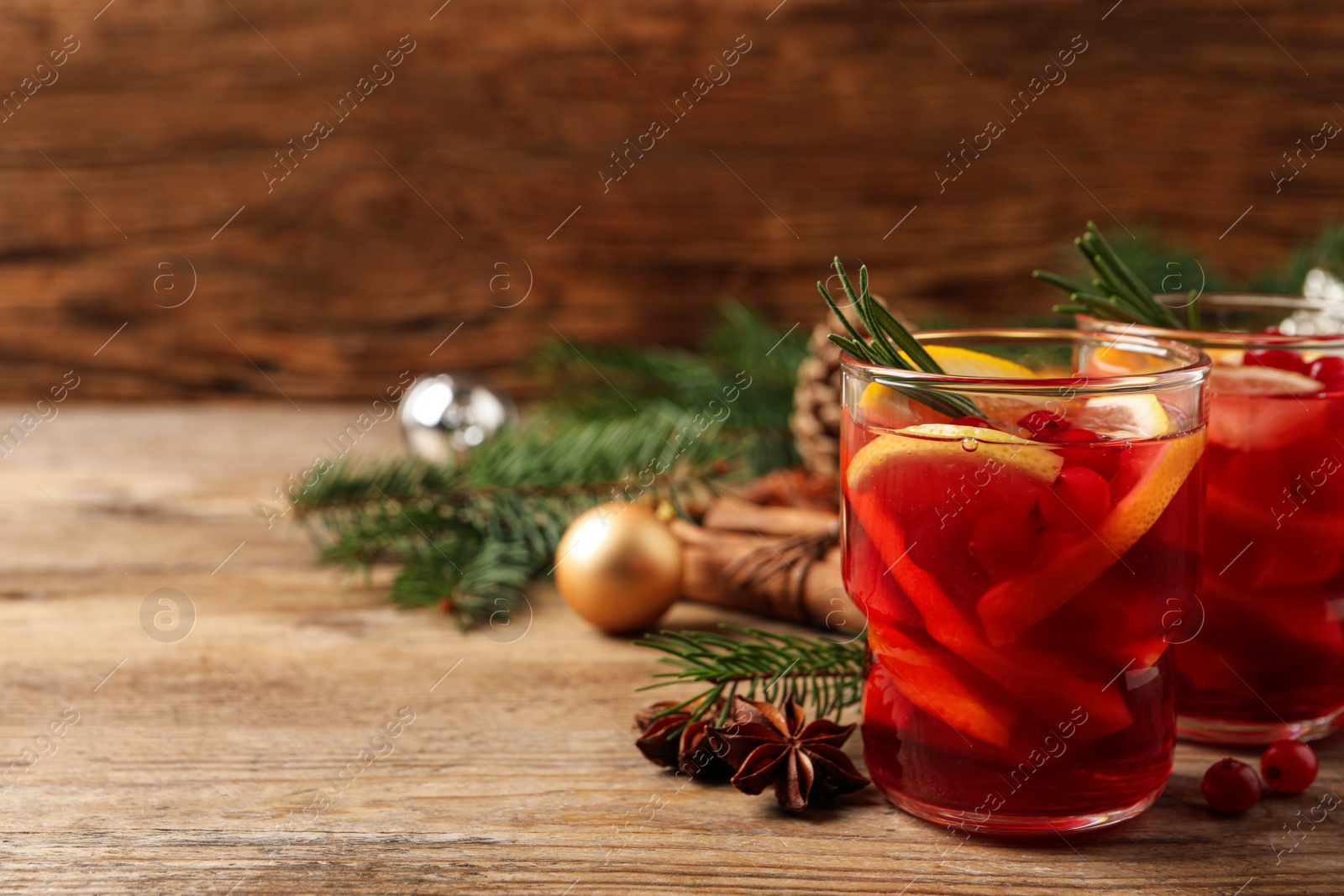 Photo of Delicious punch drink with cranberries and orange on wooden table. Space for text