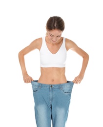 Photo of Young slim woman in old big jeans showing her diet results on white background