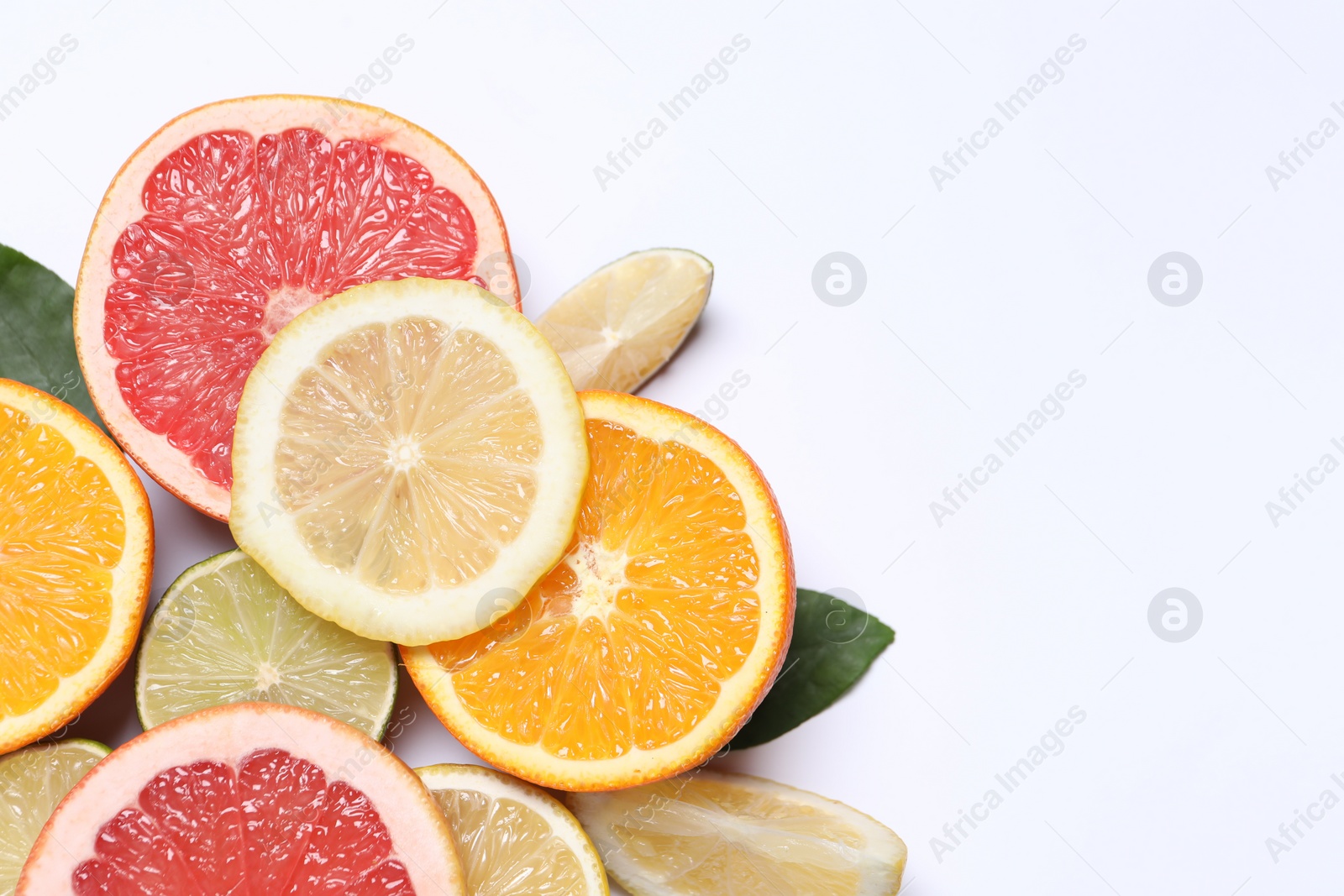 Photo of Different cut citrus fruits on white table, flat lay. Space for text