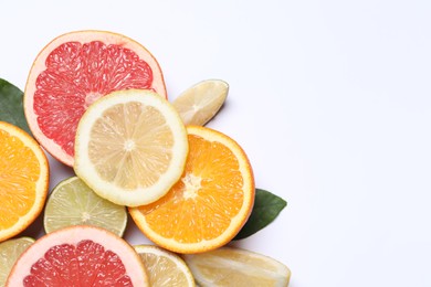 Different cut citrus fruits on white table, flat lay. Space for text