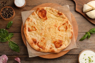 Photo of Delicious khachapuri with cheese on wooden table, flat lay