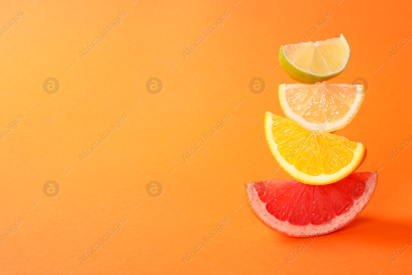 Photo of Cut fresh citrus fruits on orange background, space for text