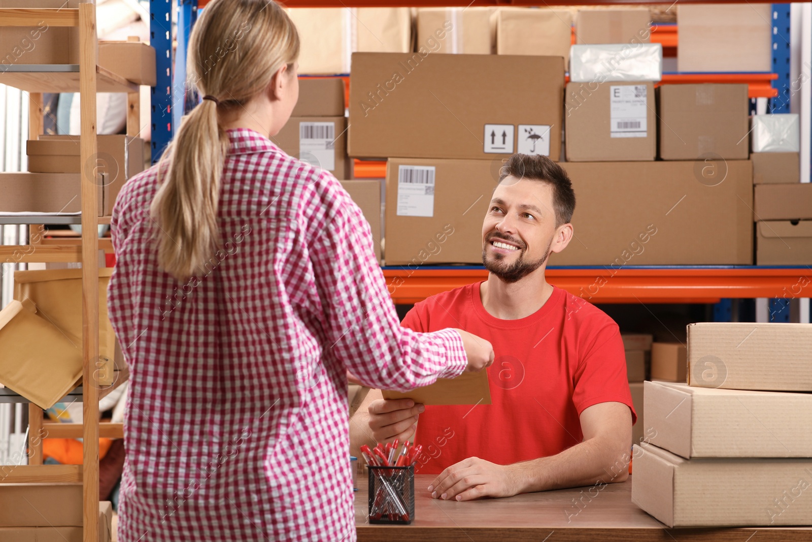 Photo of Woman receiving parcel from worker at post office