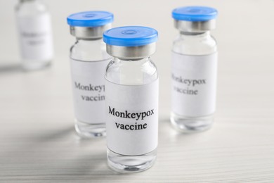 Monkeypox vaccine in glass vials on white wooden table