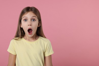 Photo of Portrait of surprised girl on pink background. Space for text