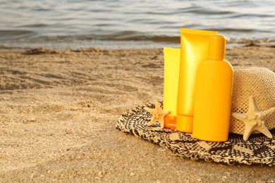 Photo of Sun protection products, hat and starfishes on sand near sea, space for text