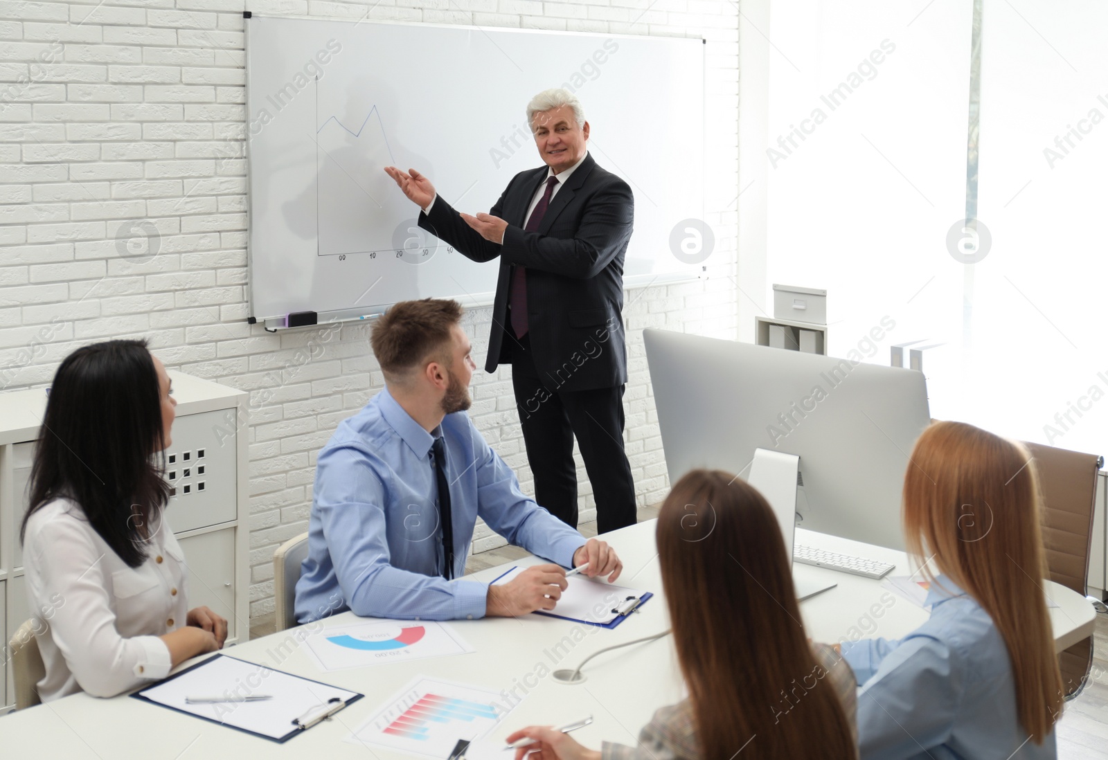 Photo of Senior business trainer working with people in office