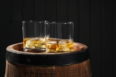 Glasses of tasty whiskey on wooden barrel