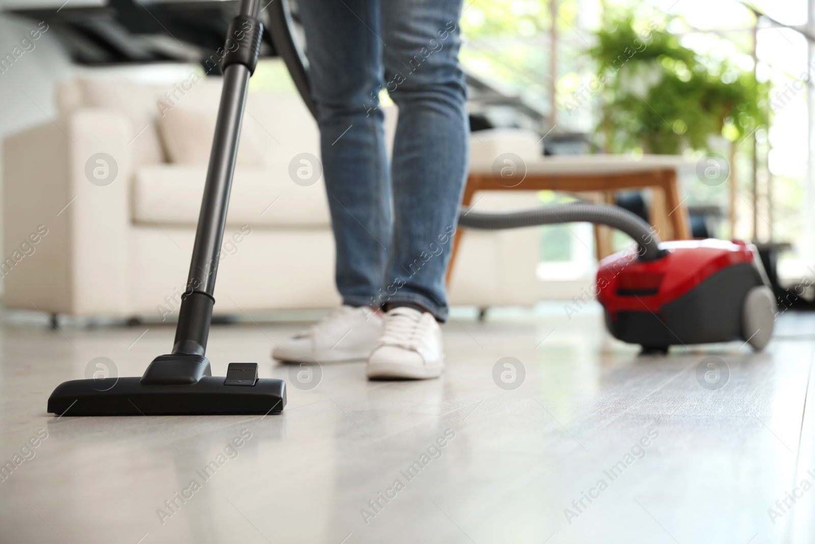 Photo of Young man using vacuum cleaner living room, closeup