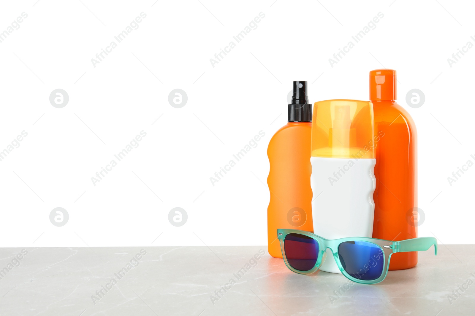 Photo of Bottles of sun protection products and glasses on table against white background