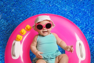 Image of Cute little baby with inflatable ring in swimming pool, top view