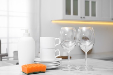 Set of clean dishes and cleaning product on table in stylish kitchen