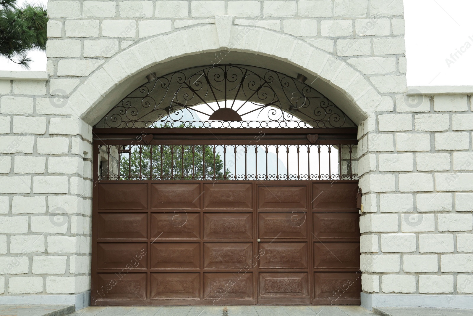 Photo of White brick wall with beautiful brown metal gates. Exterior design