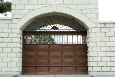 White brick wall with beautiful brown metal gates. Exterior design