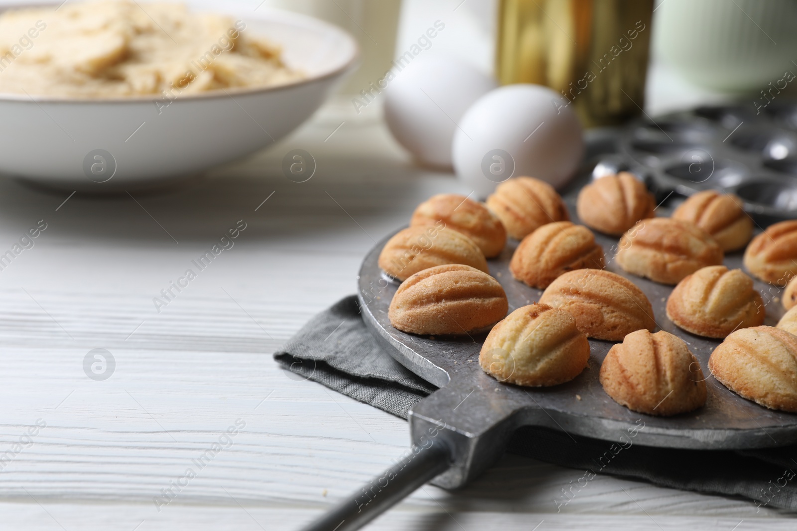 Photo of Delicious walnut shaped cookies with condensed milk and ingredients on white wooden table, closeup. Space for text