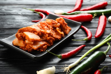 Delicious kimchi with Chinese cabbage and ingredients on black wooden table, closeup