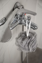 Grey shower puff hanging on faucet in bathroom, closeup