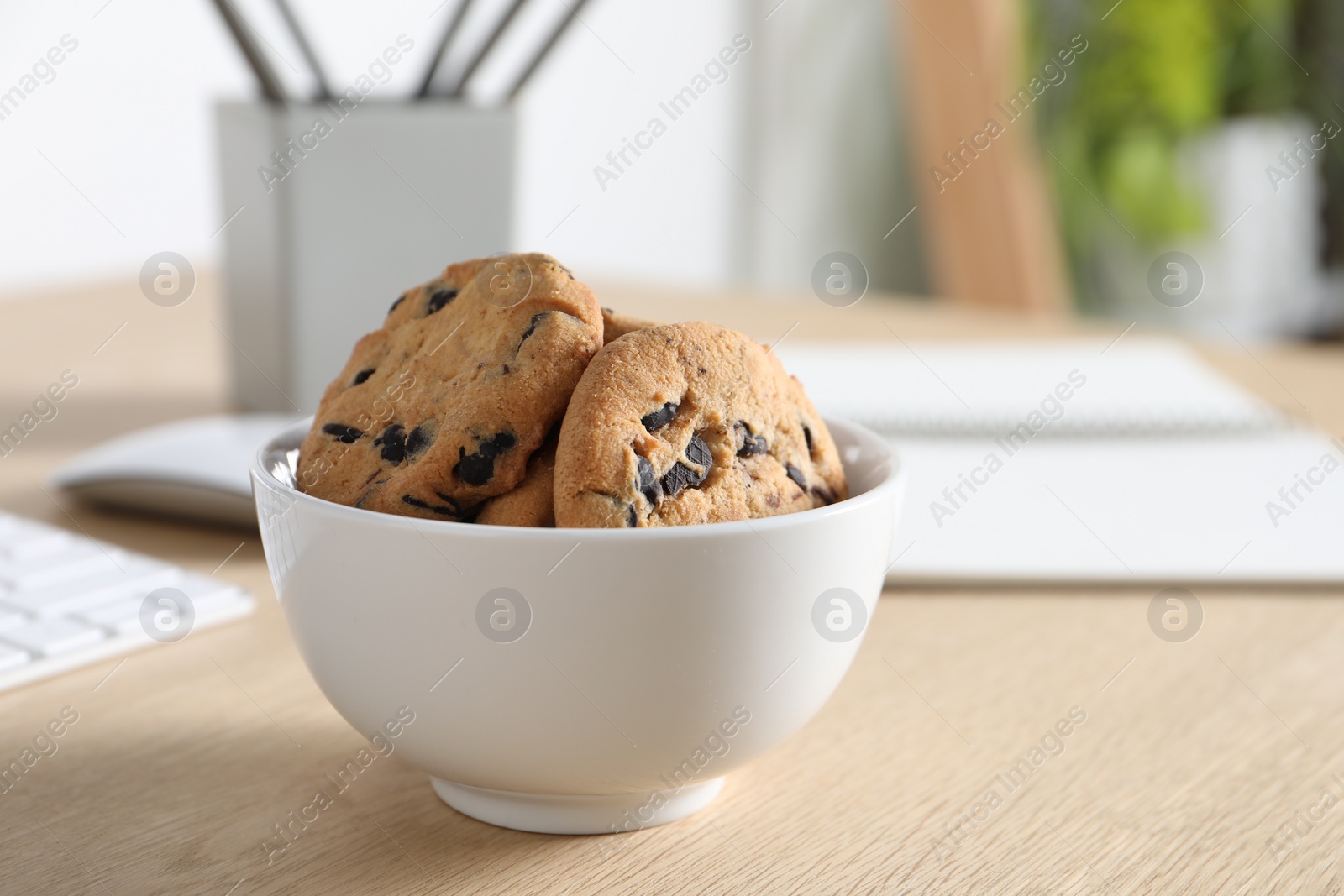 Photo of Chocolate chip cookies on wooden table at workplace. Space for text