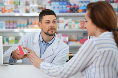 Professional pharmacist giving medicine to customer in drugstore