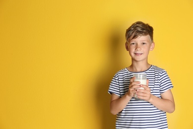 Photo of Adorable little boy with glass of milk on color background