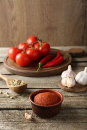 Photo of Red curry paste in bowl and ingredients on wooden table