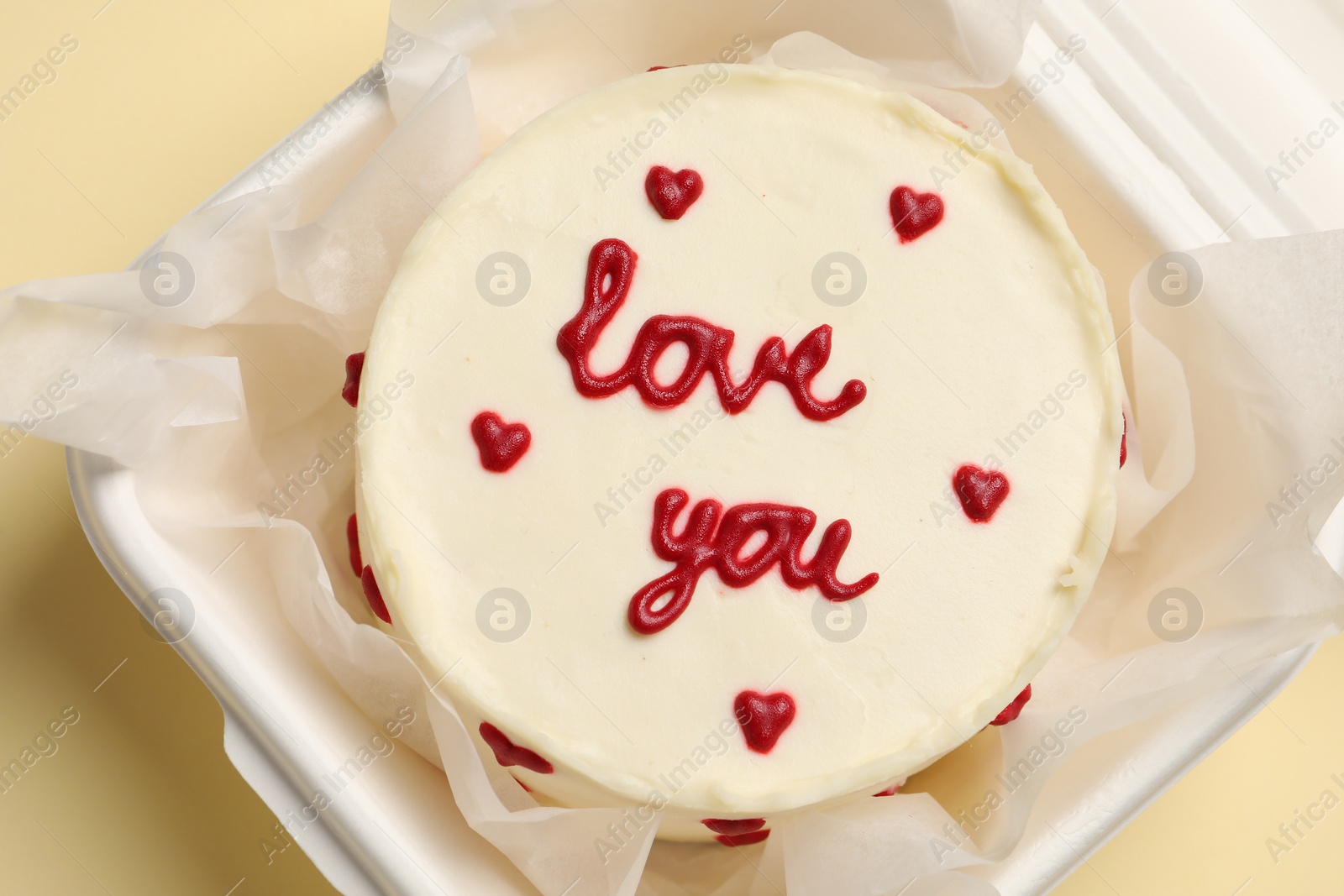 Photo of Bento cake with Love You text in takeaway box on beige table, top view. St. Valentine's day surprise