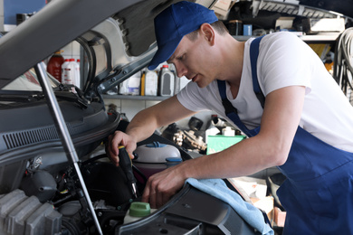 Professional auto mechanic fixing modern car in service center
