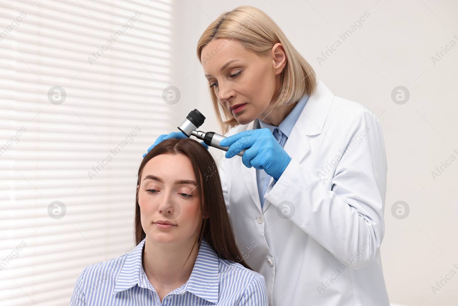 Photo of Trichologist with dermatoscope examining patient`s hair in clinic