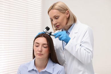 Photo of Trichologist with dermatoscope examining patient`s hair in clinic