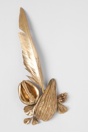 Photo of Shiny stylish golden half of walnut, avocado and feather on white background, flat lay. Decor elements