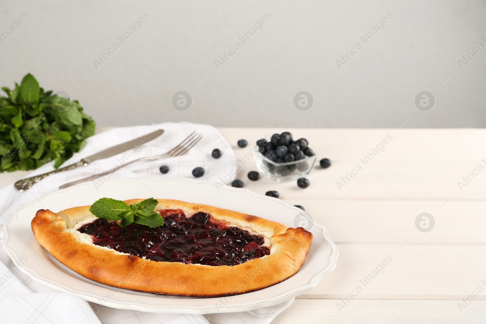 Photo of Delicious sweet cottage cheese pastry with cherry jam served on white wooden table. Space for text