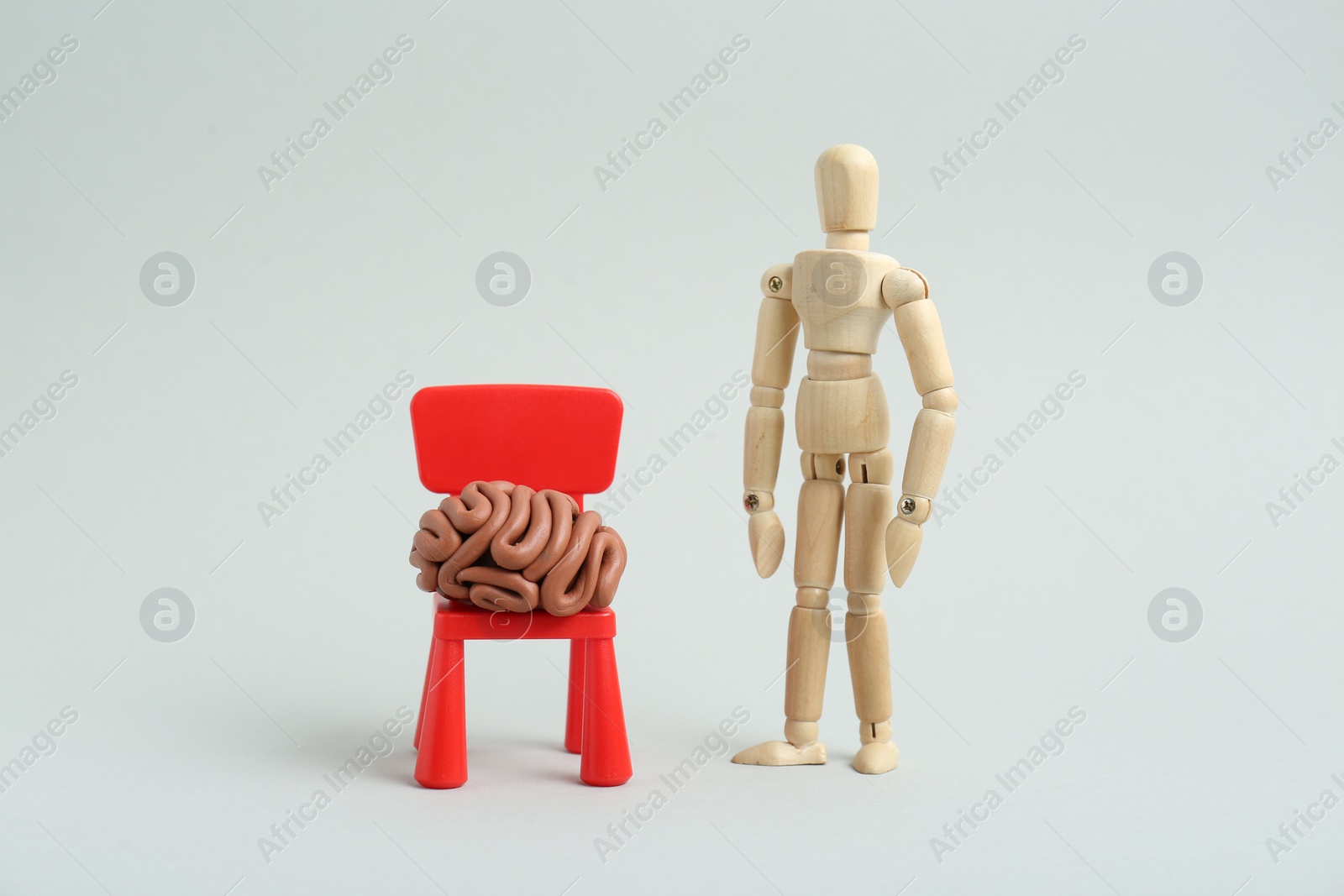 Photo of Mini chair with brain made of plasticine and wooden human model on white background