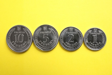 Ukrainian coins on yellow background, flat lay