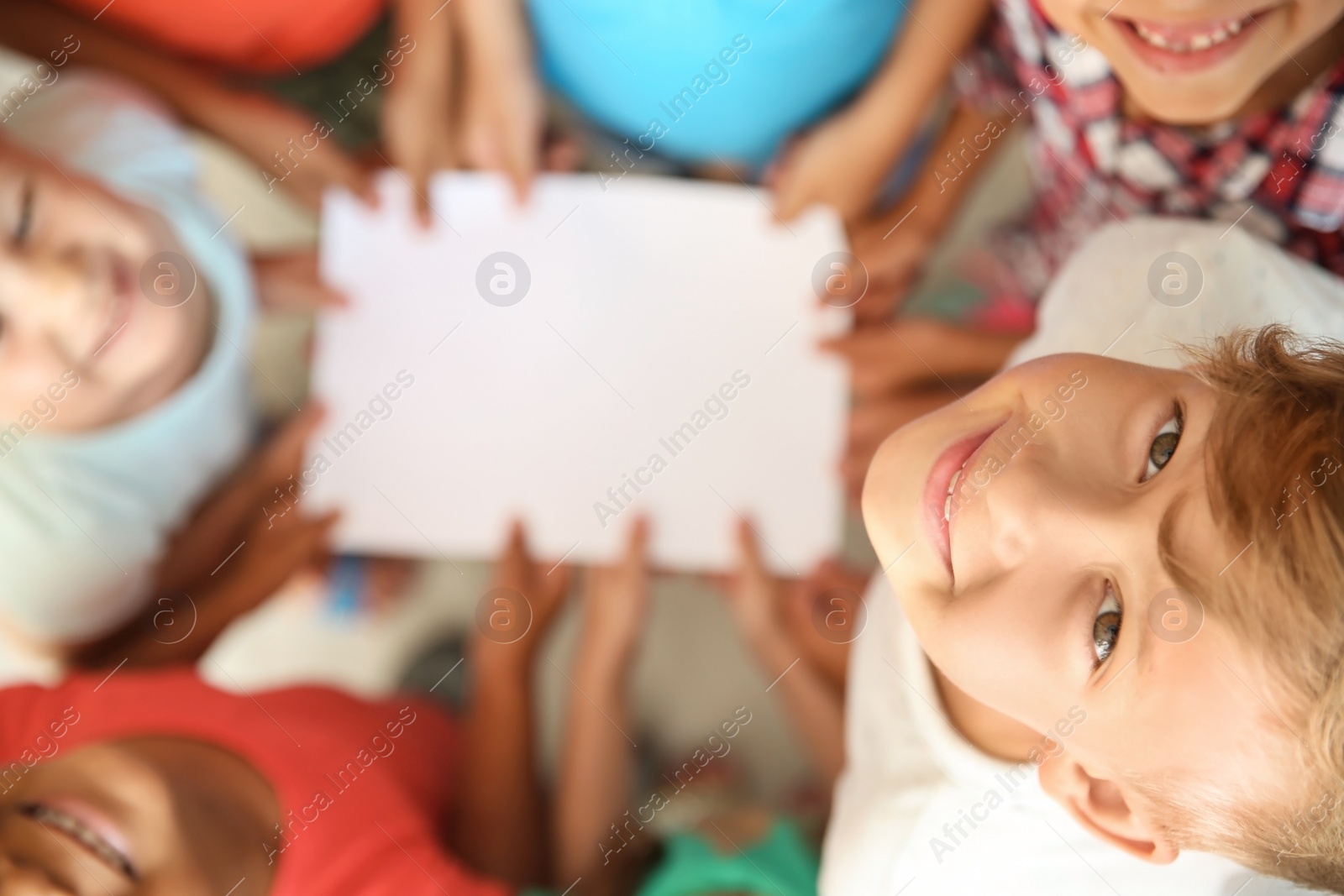 Photo of Little children with their hands together holding sheet of paper, selective focus. Unity concept
