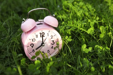 Photo of Small alarm clock on green grass, space for text