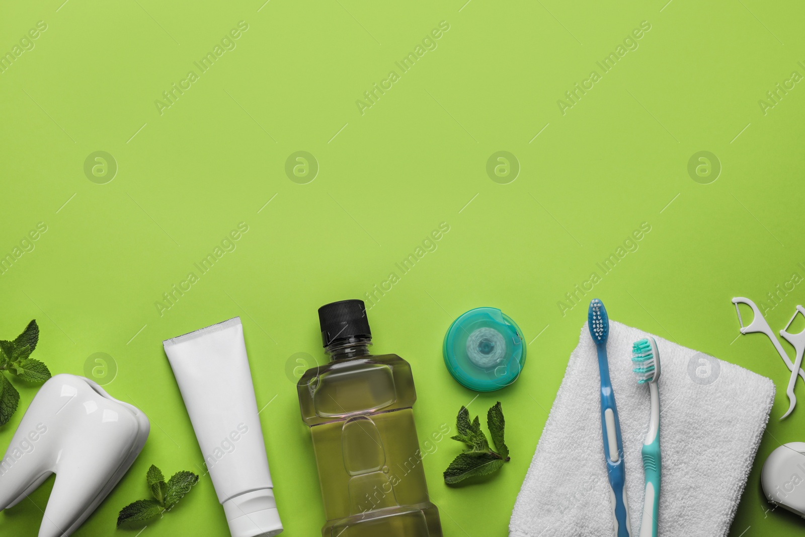 Photo of Flat lay composition with mouthwash and other oral hygiene products on light green background. Space for text