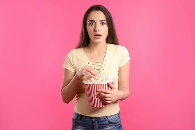 Photo of Emotional woman with popcorn during cinema show on color background