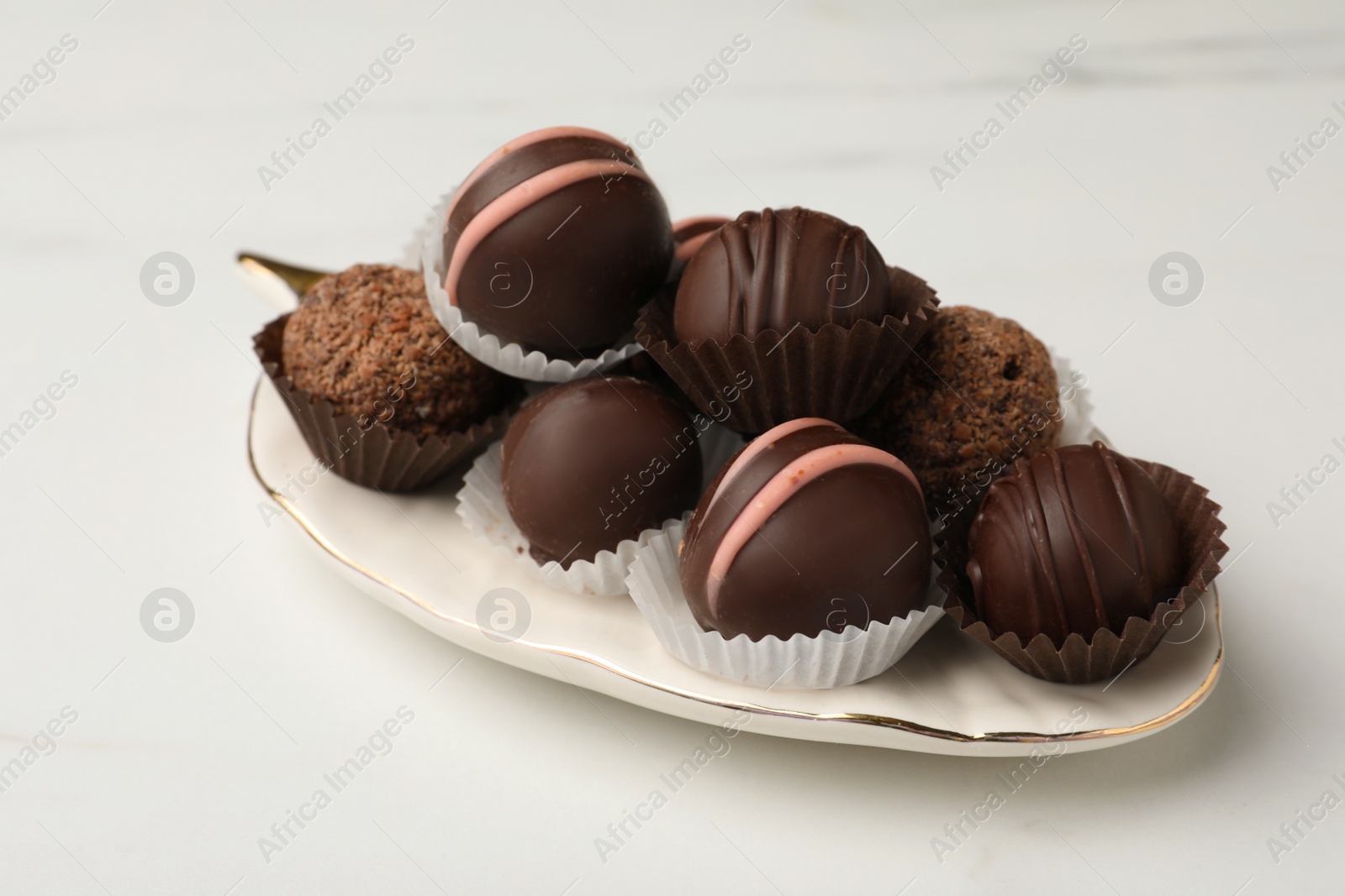 Photo of Different delicious chocolate truffles on white marble table