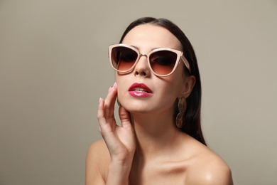 Photo of Beautiful woman in stylish sunglasses on beige background