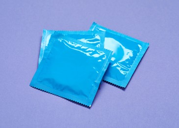 Condom packages on purple background. Safe sex