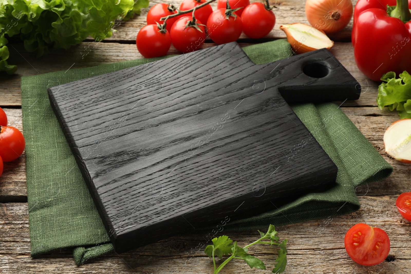 Photo of Black cutting board and products on wooden table, closeup