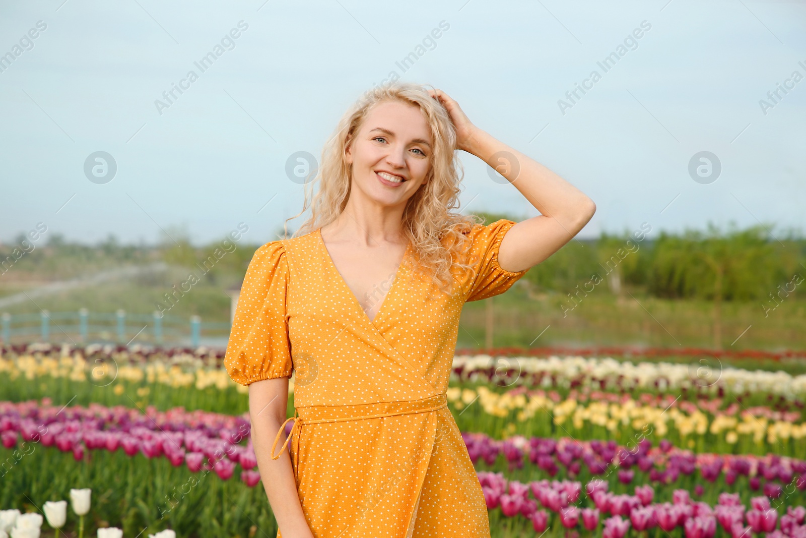 Photo of Happy woman in beautiful tulip field outdoors