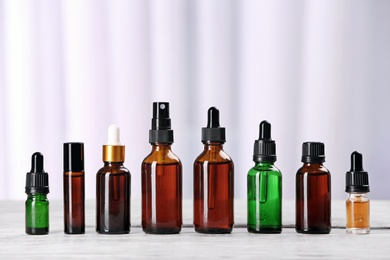 Bottles of essential oils on table against light background. Cosmetic products