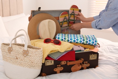 Photo of Woman packing suitcase for summer vacation in bedroom, closeup