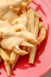 Photo of Delicious french fries with cheese sauce on plate, closeup